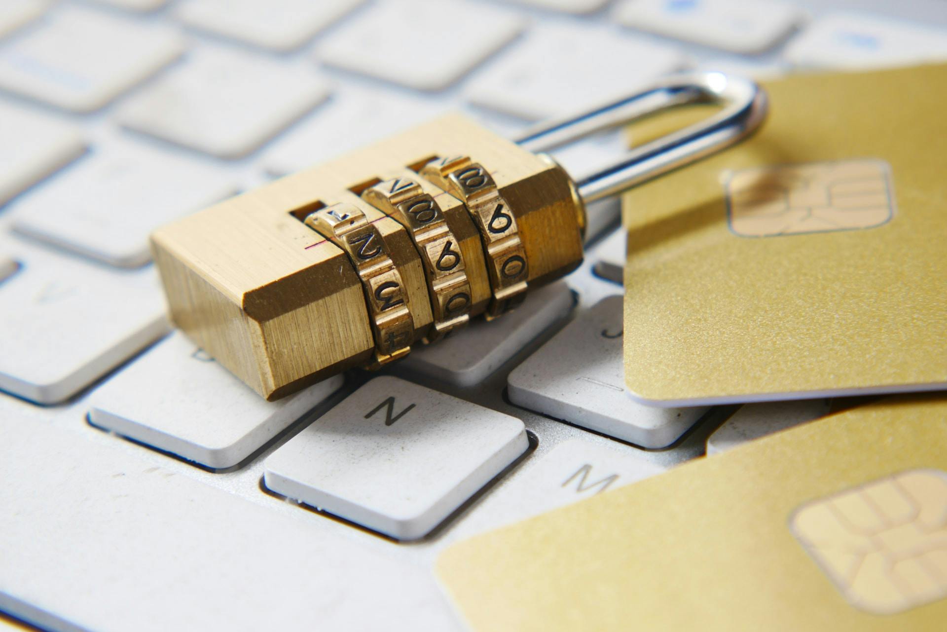 A golden padlock on a laptop keyboard with credit cards underneath