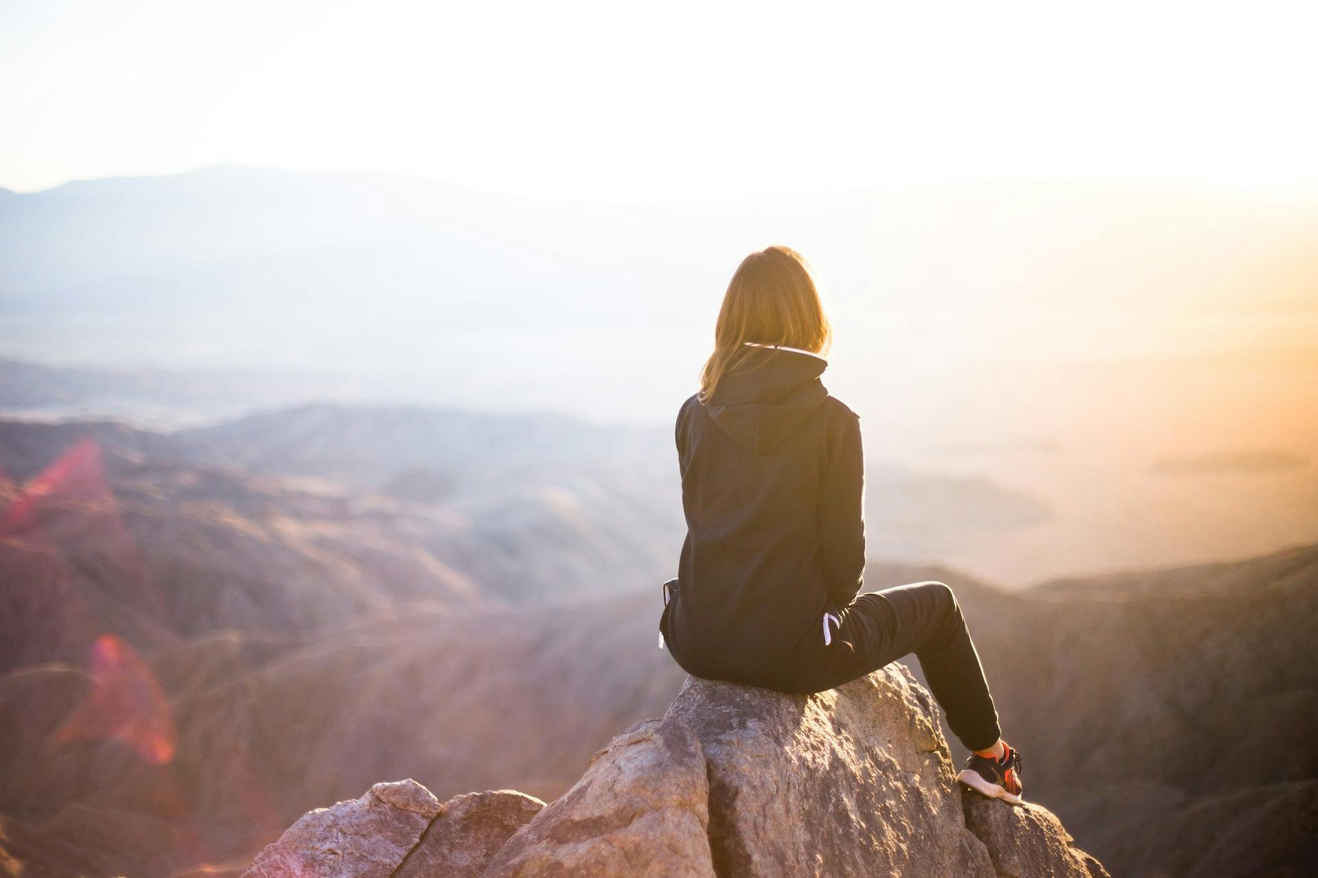 A woman on a mountain top looking out in the horizon
